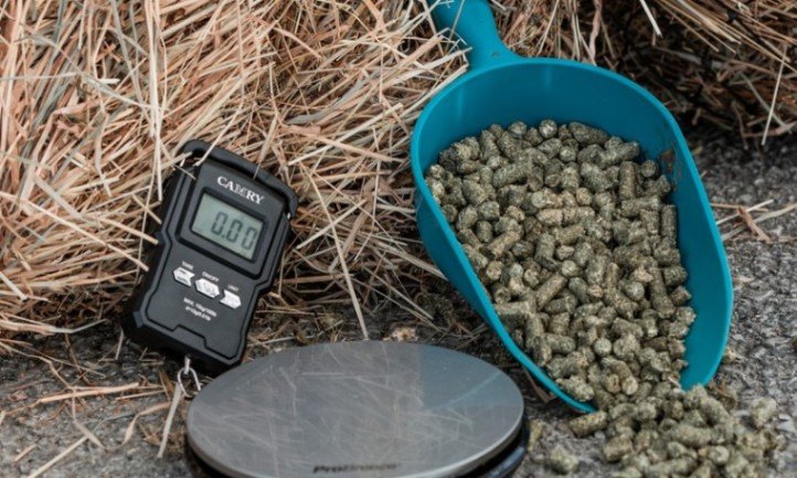 Digitalna vaga, kanta s konjskom hranom i hrpa sijena na radnoj površini